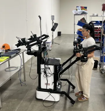 Senior Robot Pilot Sofia Infante operates a leader-follower rig to generate robot training data.