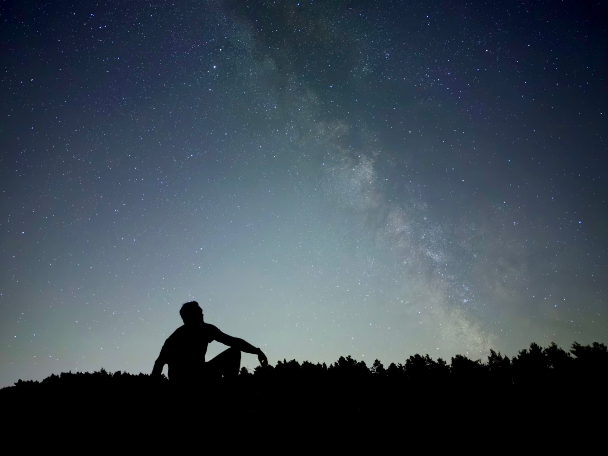 A photograph captured on iPhone 18 Pro using Night mode shows a person silhouetted against a starry sky.